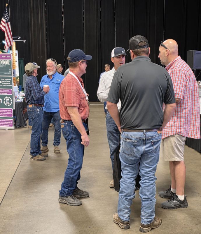A group of five attendees in conversation on the trade show floor