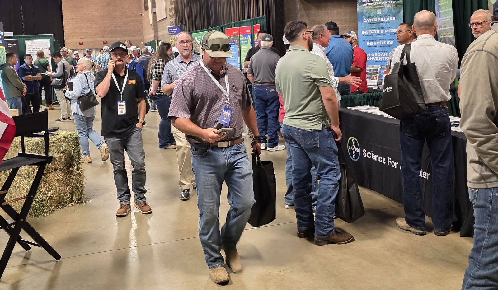 A packed trade show aisle between sessions on Day 1, attendees walking and talking between booths