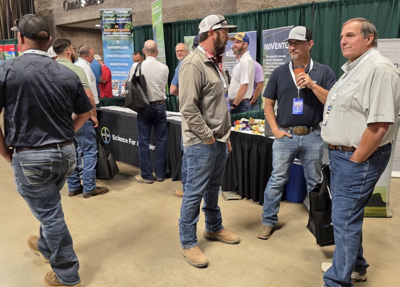 Four attendees talking and laughing in a trade show aisle