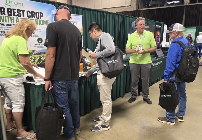 A crowd of attendees at booths along a trade show aisle on Day 1