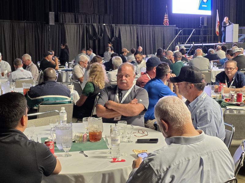 Attendees around a lunch table with the full Expo Hall behind them