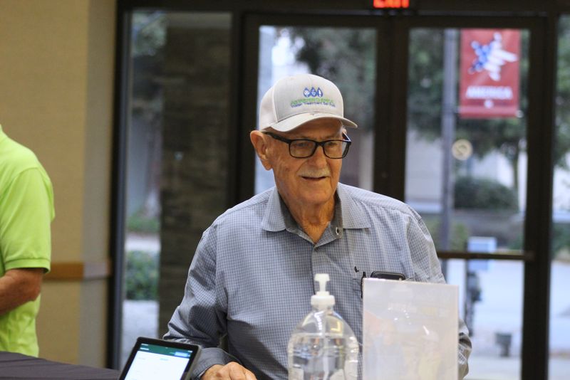 A smiling attendee in a cap at the Day 1 registration desk