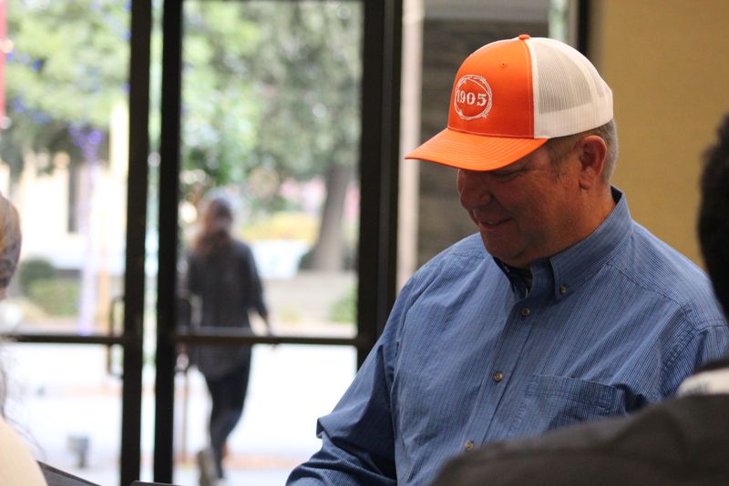 An attendee in an orange cap smiling at the registration desk