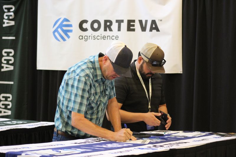 Two attendees signing in for CE credit at the Corteva Agriscience table