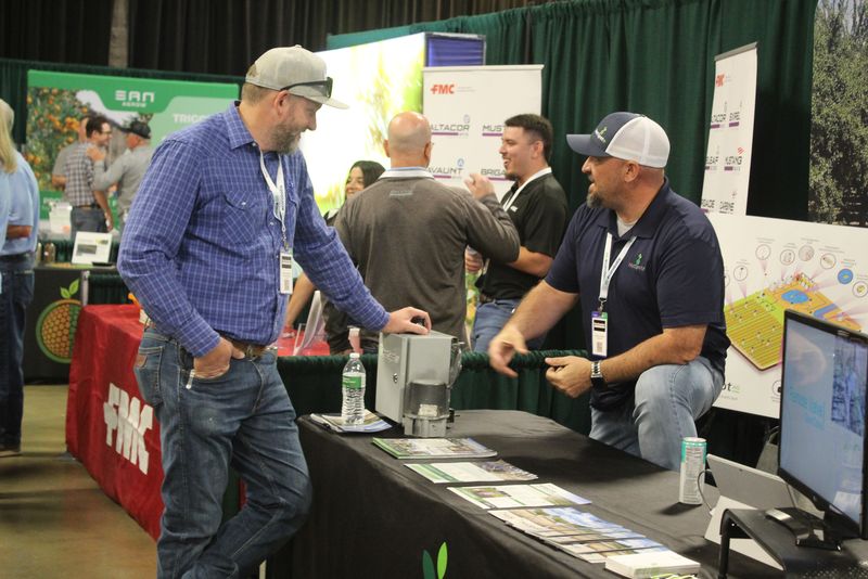 Three attendees laughing together at a trade show booth