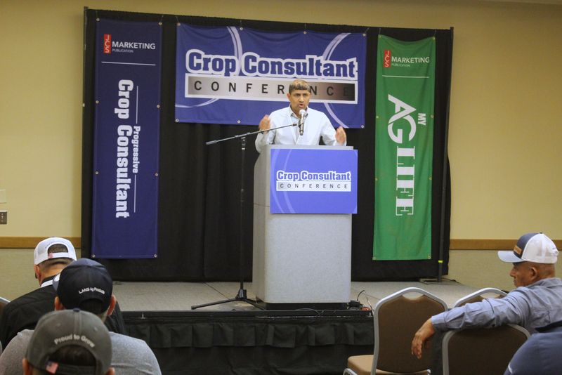 A speaker at the Crop Consultant Conference podium in a breakout room