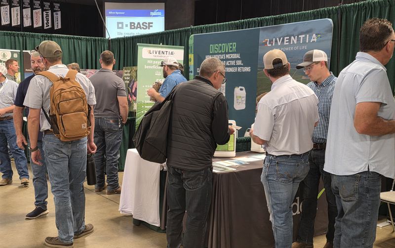 A crowd of attendees at a booth on Day 2