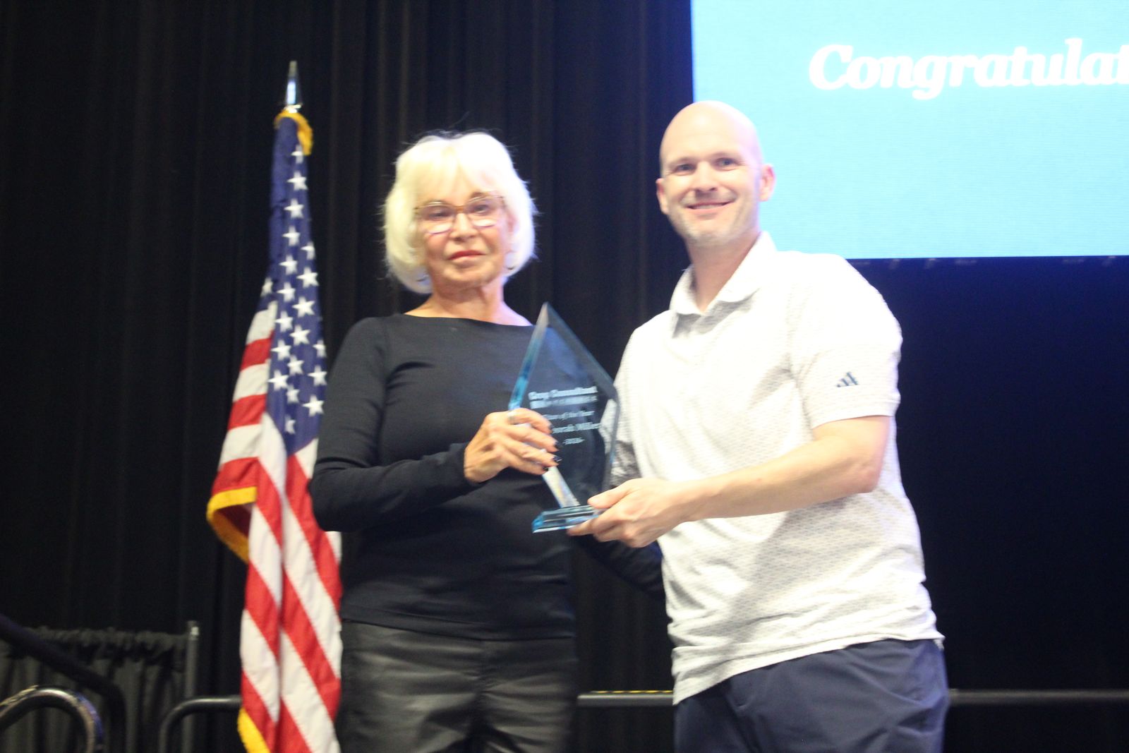 Deborah Miller holding her 2026 Titan of the Year award on stage
