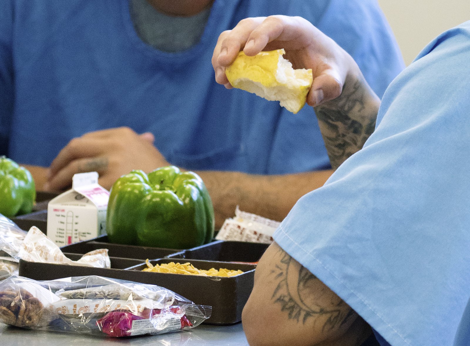 An incarcerated individual eats a meal featuring fresh California-grown produce, including a green bell pepper, at California State Prison Solano